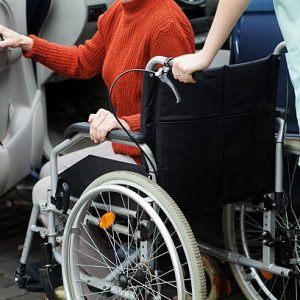 Caregiver helping disabled lady get into the car