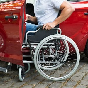 Close-up Of A Disabled Man In Wheelchair Getting In His Car