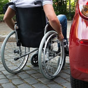 Close-up Of A Man Sitting On A Wheelchair Near His Car
